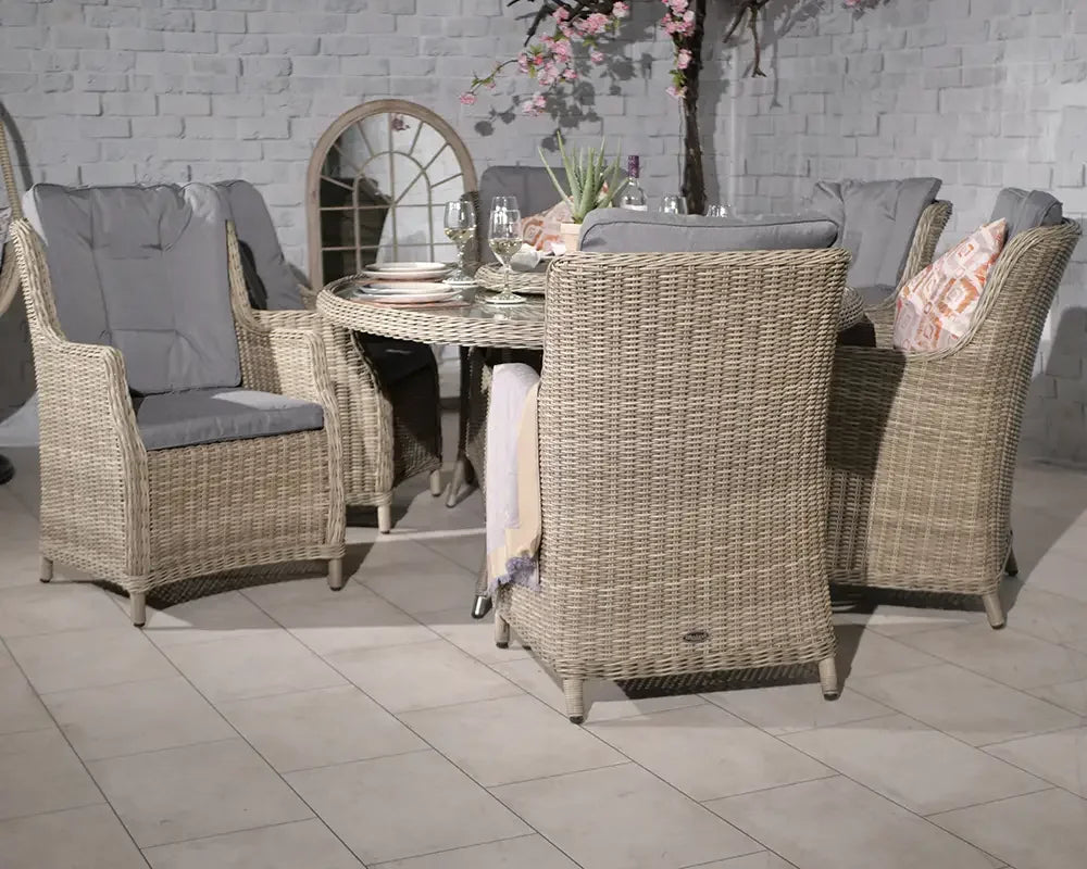 Rattan dining set with cushioned armchairs and round glass-top table on tiled floor