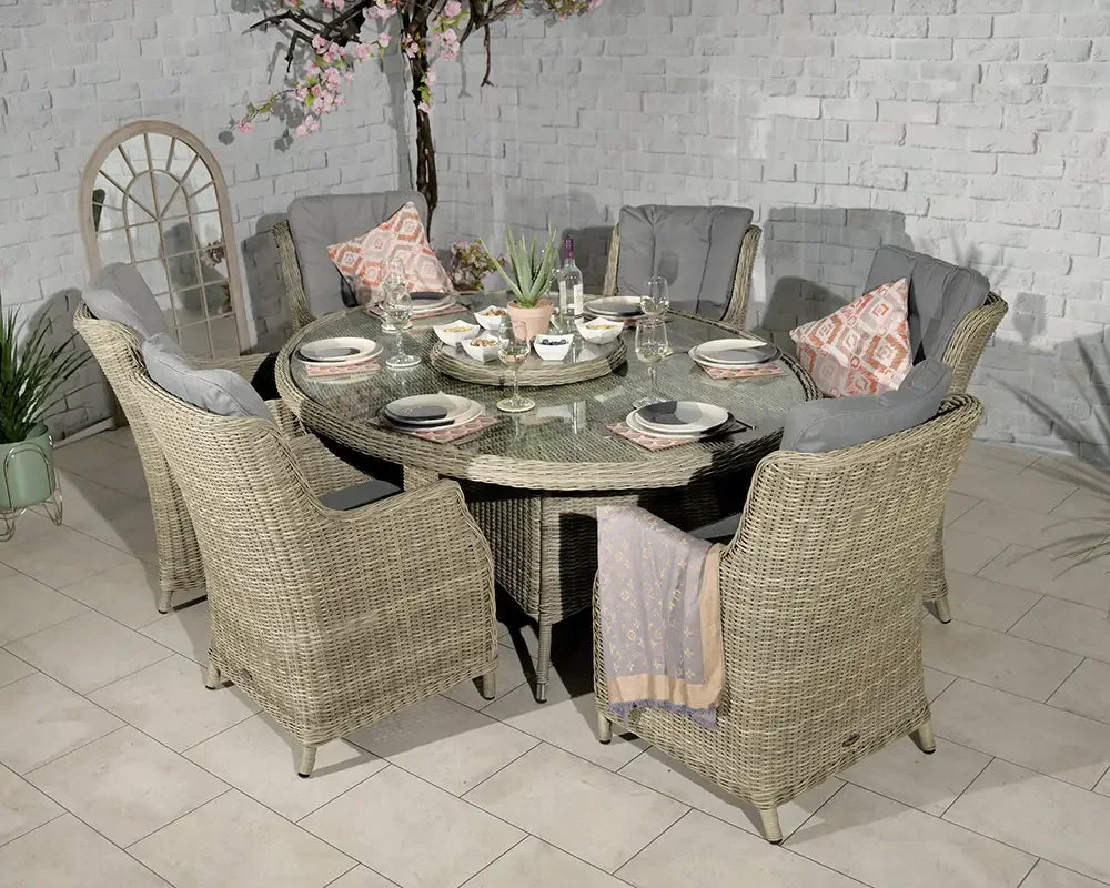 Rattan garden dining set with six chairs, grey cushions, and round glass table top