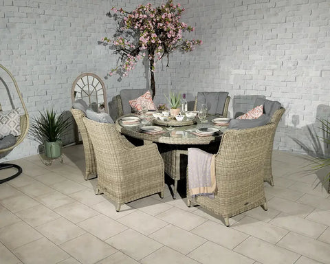 Rattan garden dining set with six cushioned chairs and glass-topped round table indoors