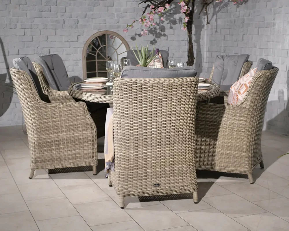 Beige rattan dining set with six cushioned chairs and round glass table, indoor setting