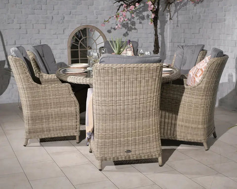 Beige rattan dining set with six cushioned chairs and round glass table, indoor setting