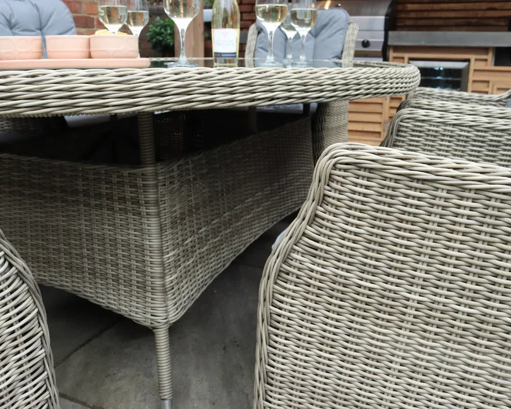 Light grey rattan dining set with glass top table and matching woven chairs outdoors