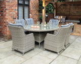Rattan outdoor dining set with six cushioned chairs and glass top table on patio