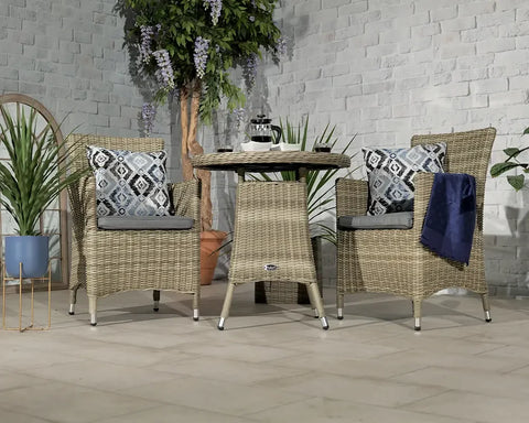 Natural rattan garden dining set with cushions and round table, styled with plants