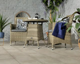 Rattan garden dining set with two armchairs, cushions, and a rectangular table on patio
