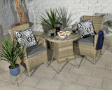 Rattan bistro set with glass-top table, two grey cushioned chairs and patterned cushions