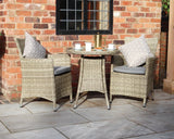 Rattan garden bistro set with round table, two armchairs, cushions and coffee cups outdoors