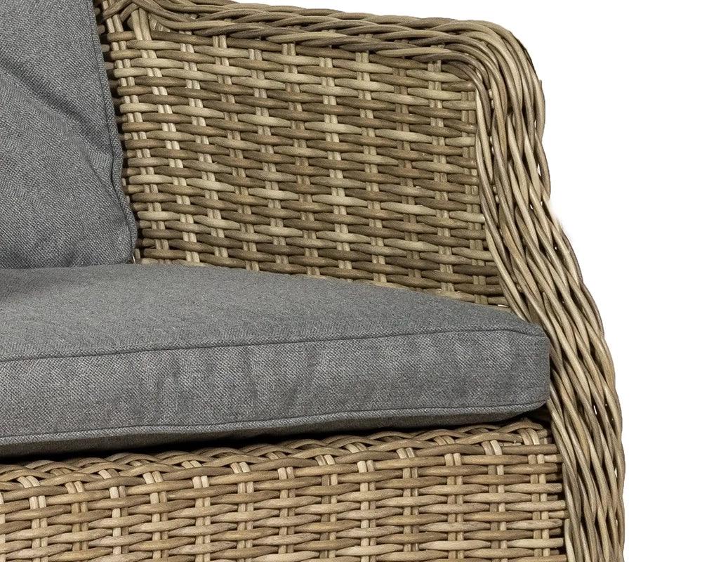 Closeup of rattan armchair with grey cushion, highlighting woven texture and fabric seat