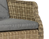 Closeup of rattan armchair with grey cushion, highlighting woven texture and fabric seat