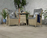 Rattan garden bistro set with glass top table, two cushioned chairs, and decorative plants