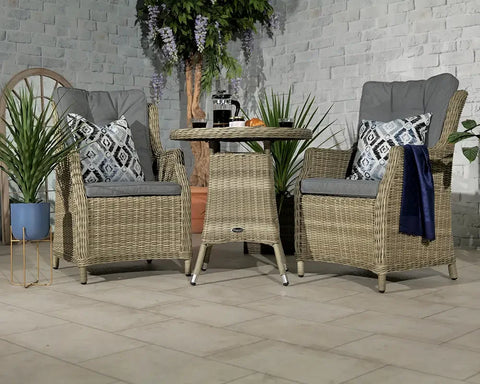 Rattan bistro set with two grey cushioned chairs and round table in a patio setting