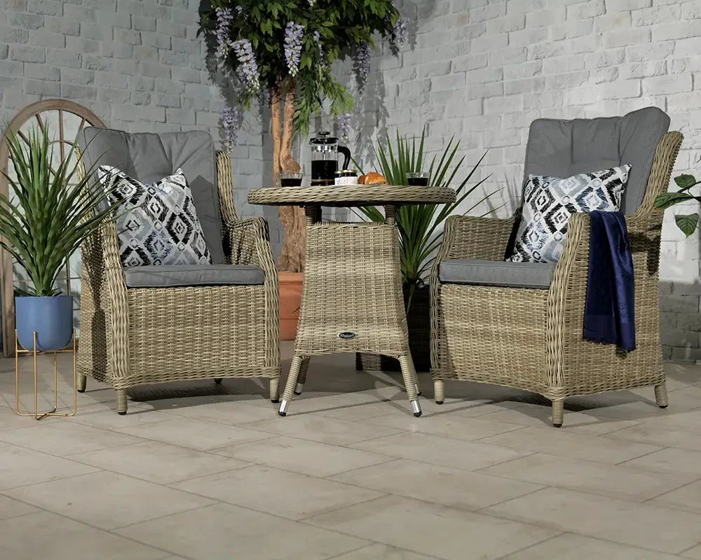 Rattan bistro set with two grey cushioned chairs and round table in a patio setting