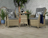 Rattan bistro set with two grey cushioned chairs and round table in a patio setting