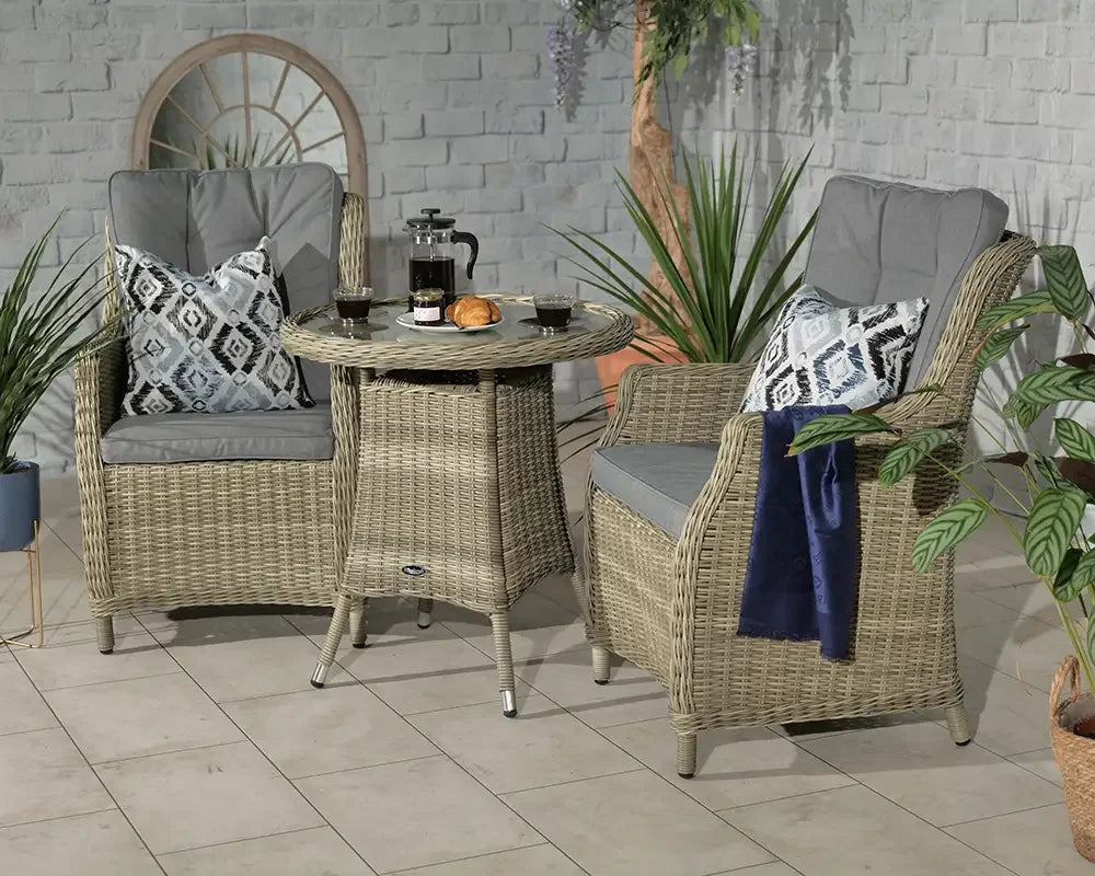 Rattan garden bistro set with two armchairs, grey cushions, and round table on patio