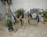 Rattan bistro set with two grey cushioned chairs and glass table in a modern indoor setting