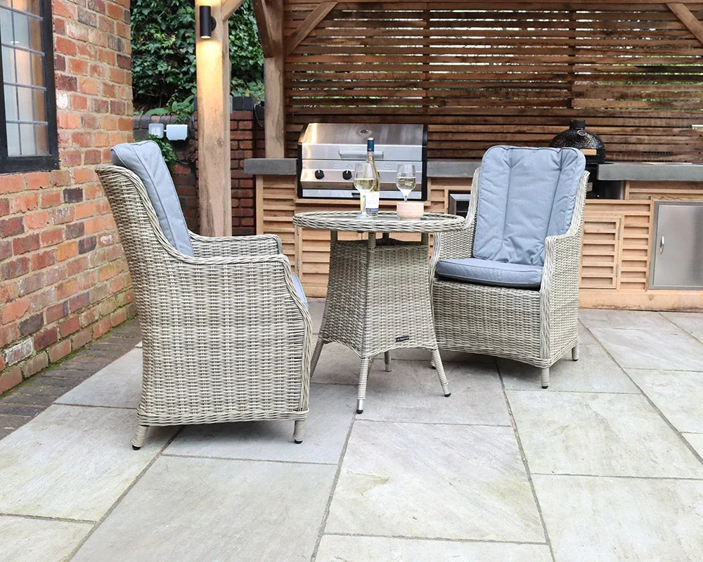 Rattan garden bistro set with two cushioned chairs and round table on patio