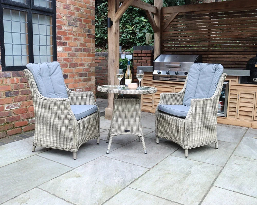 Rattan garden bistro set with two cushioned armchairs and round table on patio