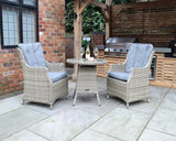 Rattan garden bistro set with two cushioned armchairs and round table on patio