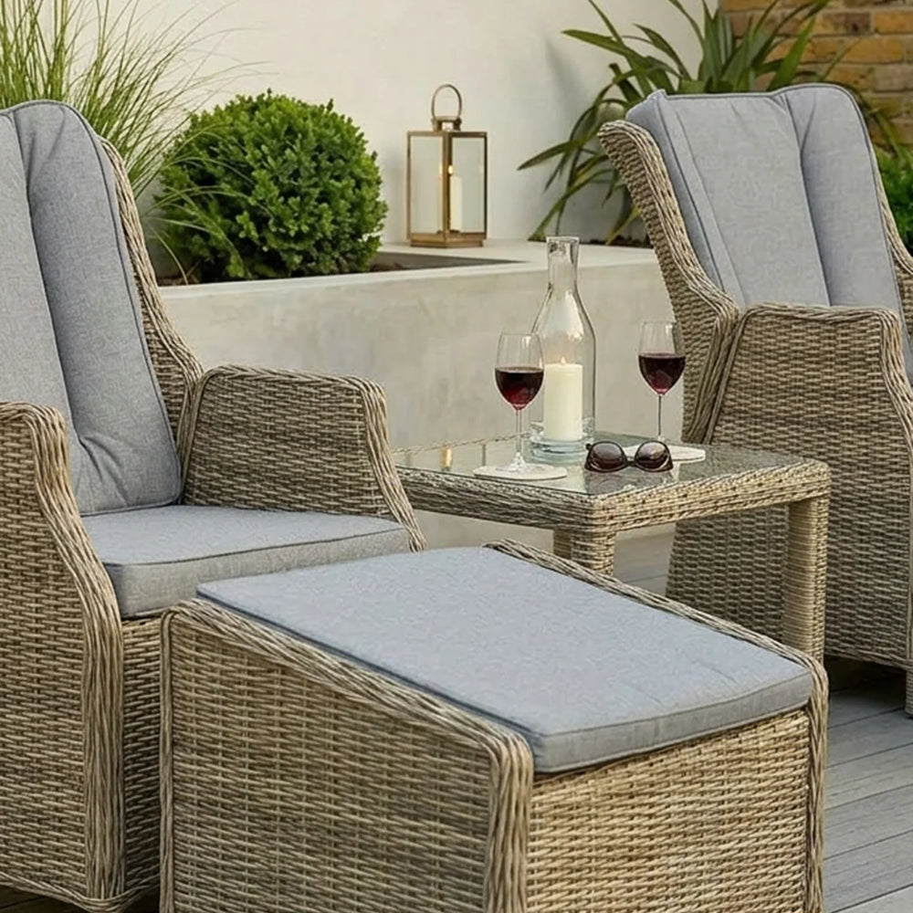Rattan garden lounge set with two chairs, ottoman, side table, and grey cushions on patio