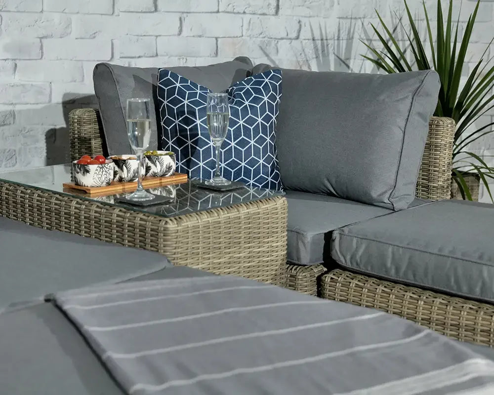 Grey rattan outdoor sofa set with glass coffee table and blue patterned cushion