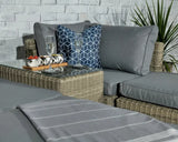 Grey rattan outdoor sofa set with glass coffee table and blue patterned cushion