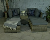 Rattan corner sofa set with grey cushions, striped throw, and glass top table on patio