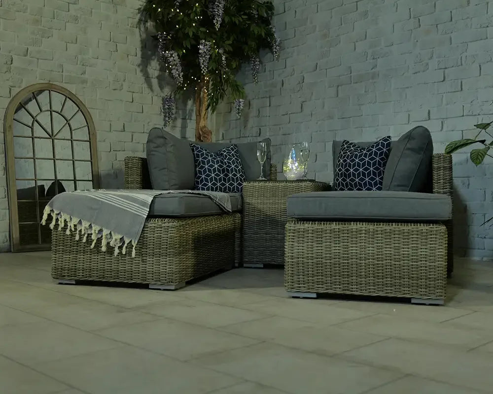 Rattan garden furniture set with grey cushions and accent pillows in patio seating area