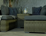 Rattan garden furniture set with grey cushions, patterned pillows and glass tabletop