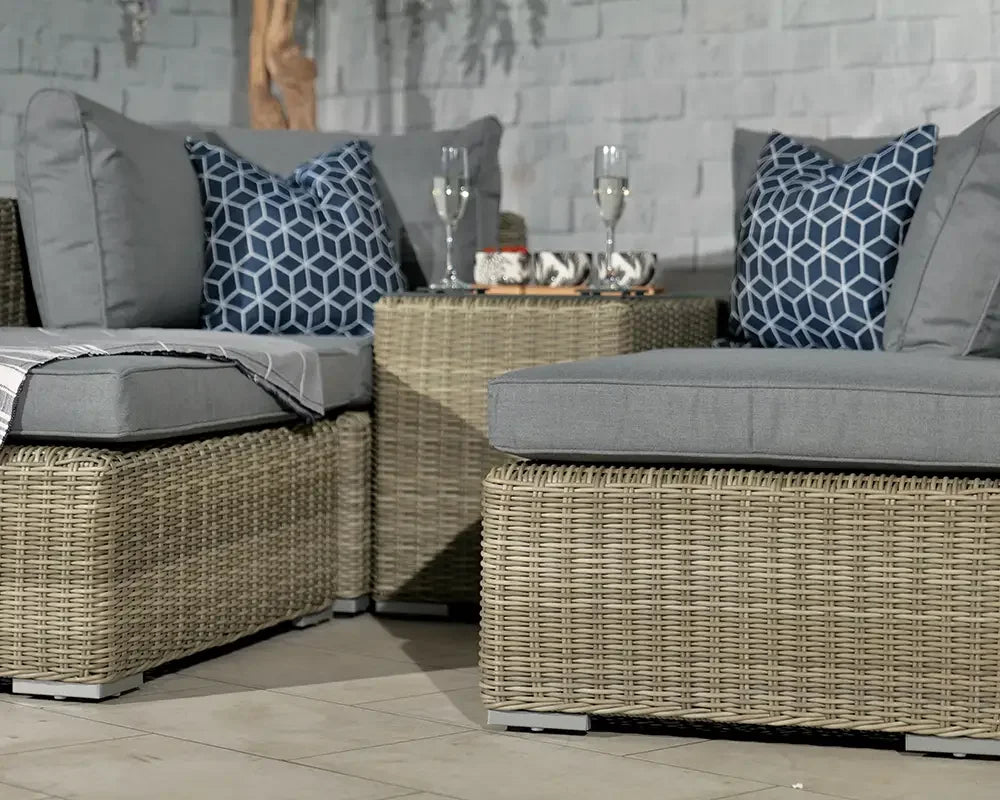 Grey rattan outdoor sofa set with blue geometric cushions and coffee table