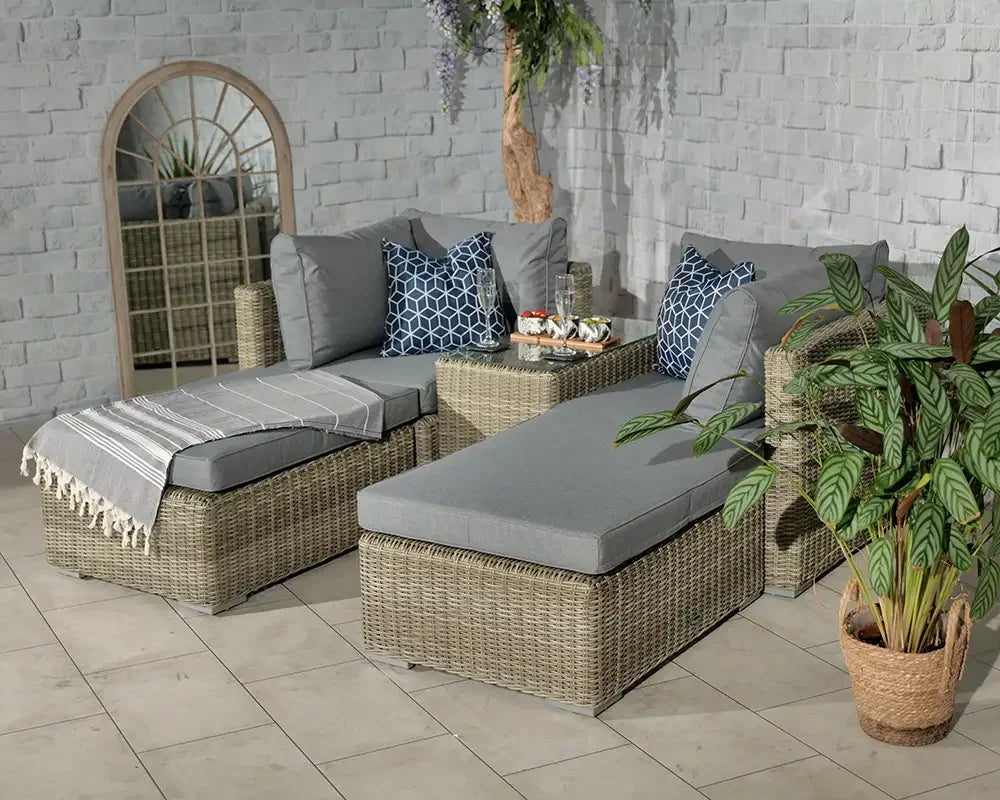 Rattan garden furniture set with grey cushions, geometric pillows and a plant in tiled room