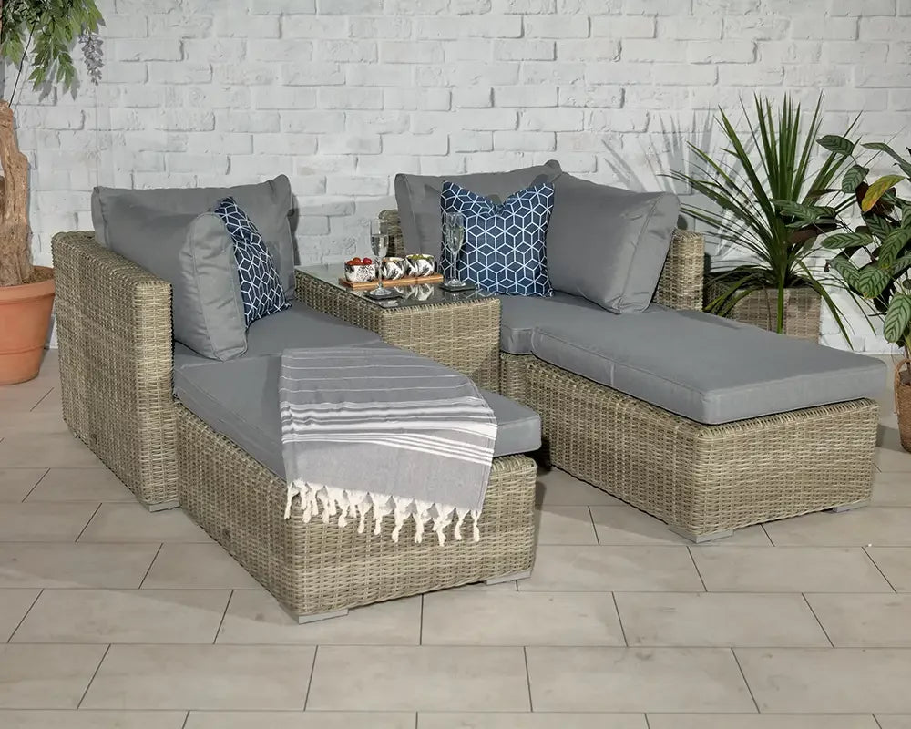 Grey rattan garden sofa set with cushions, throw and decorative pillows on tiled patio