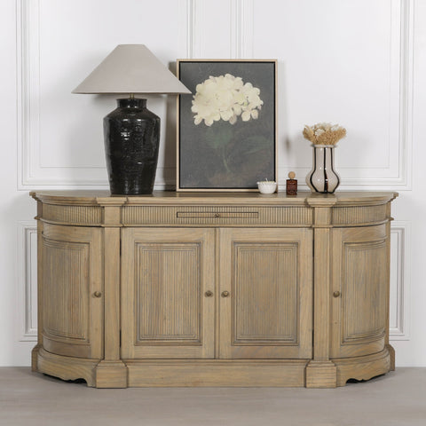 Rustic wooden buffet sideboard with fluted design, styled with a lamp, vase, and artwork.