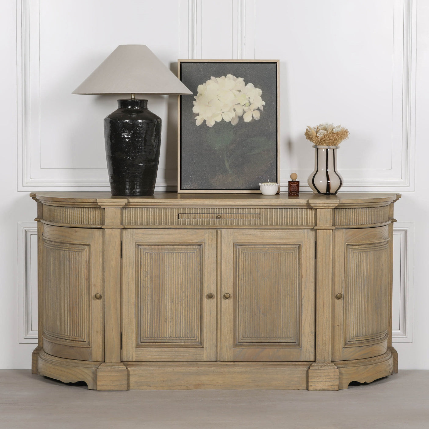 Rustic wooden buffet sideboard with fluted design, styled with a lamp, vase, and artwork.