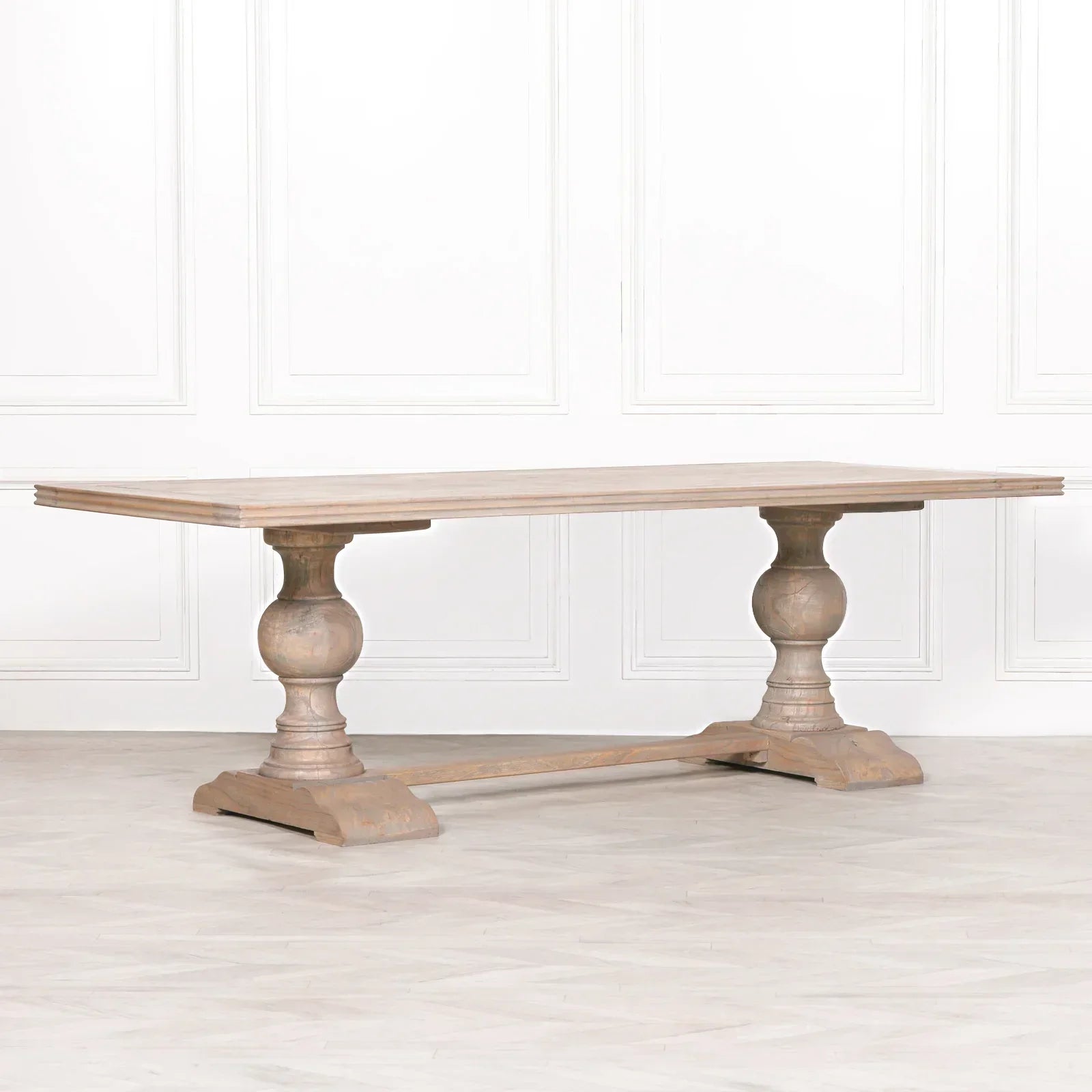 Oak dining table with trestle base and carved pedestal legs in light wood finish