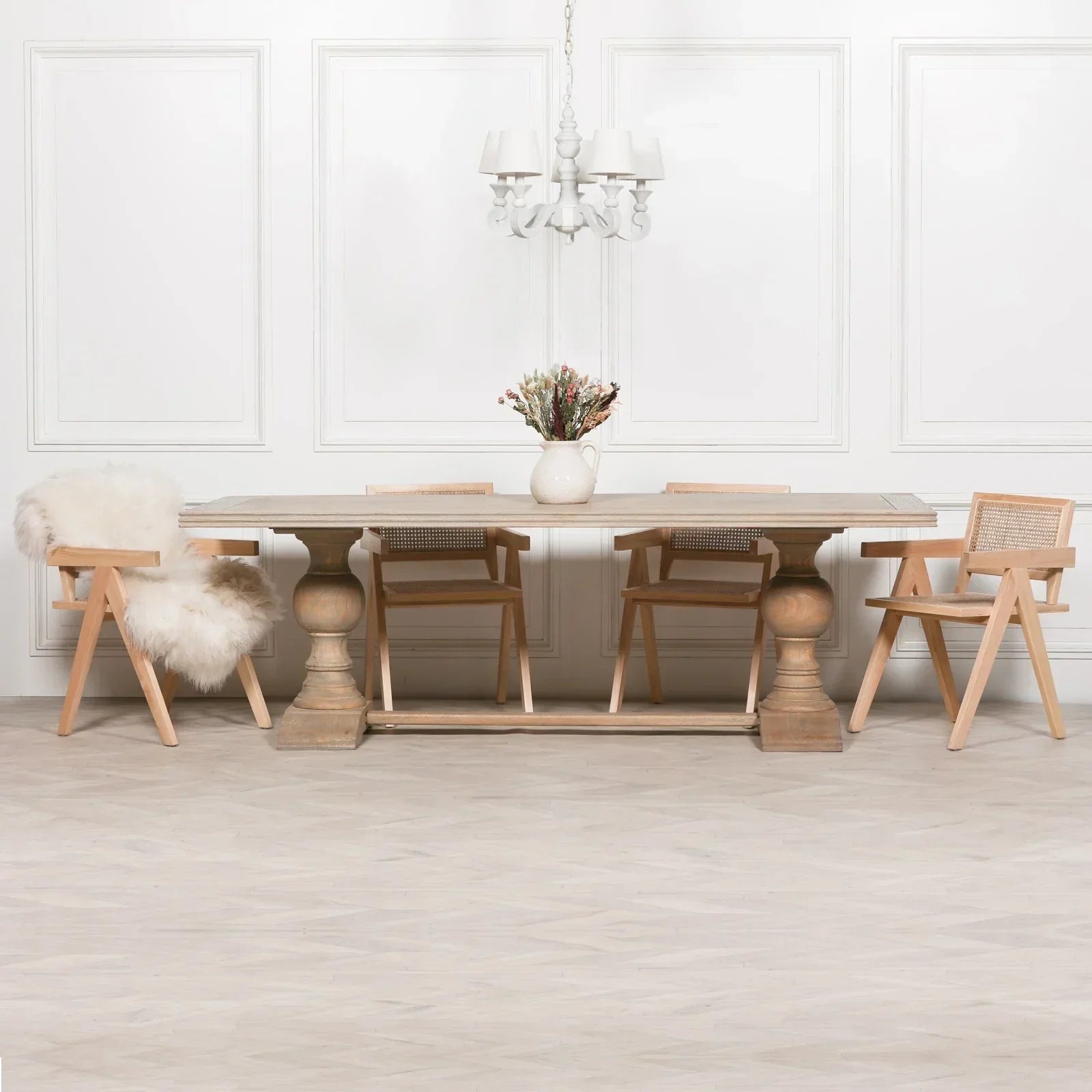 Wood dining table with four cane back chairs and vase centerpiece in neutral room
