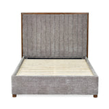 Side view of upholstered bed frame in grey fabric with wooden slats and tall channel-tufted headboard