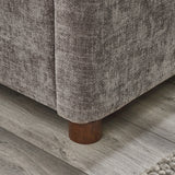 Close-up corner view of rounded wooden bed leg against wood floor and grey upholstery