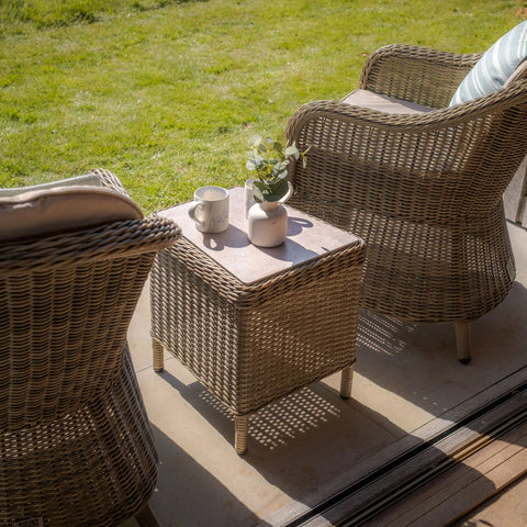 Rattan garden furniture set with two armchairs and a small table on patio