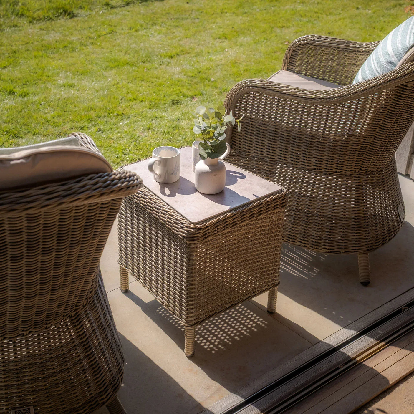 Rattan garden furniture set with two armchairs and a small table on patio