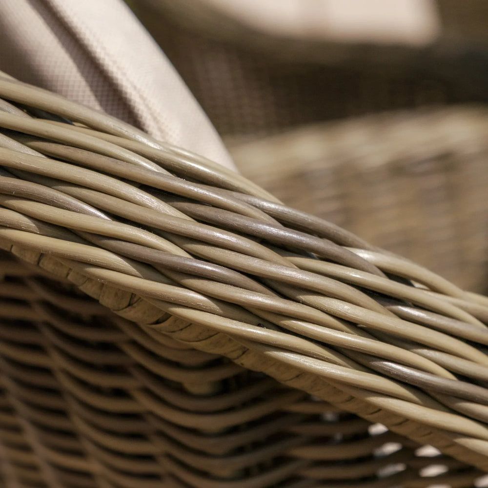 Closeup of woven rattan garden furniture arm with beige cushion fabric detail