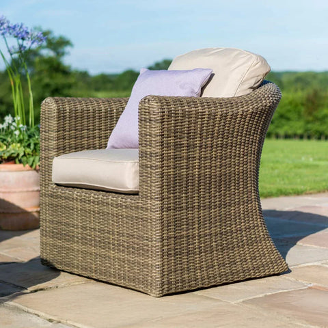 Brown rattan outdoor armchair with beige cushion and lilac pillow on patio
