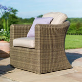 Brown rattan outdoor armchair with beige cushion and lilac pillow on patio