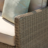 Close-up of rattan outdoor sofa arm with beige cushion and light green pillow