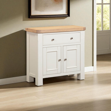 White sideboard with wooden top in a room with a window and framed picture.