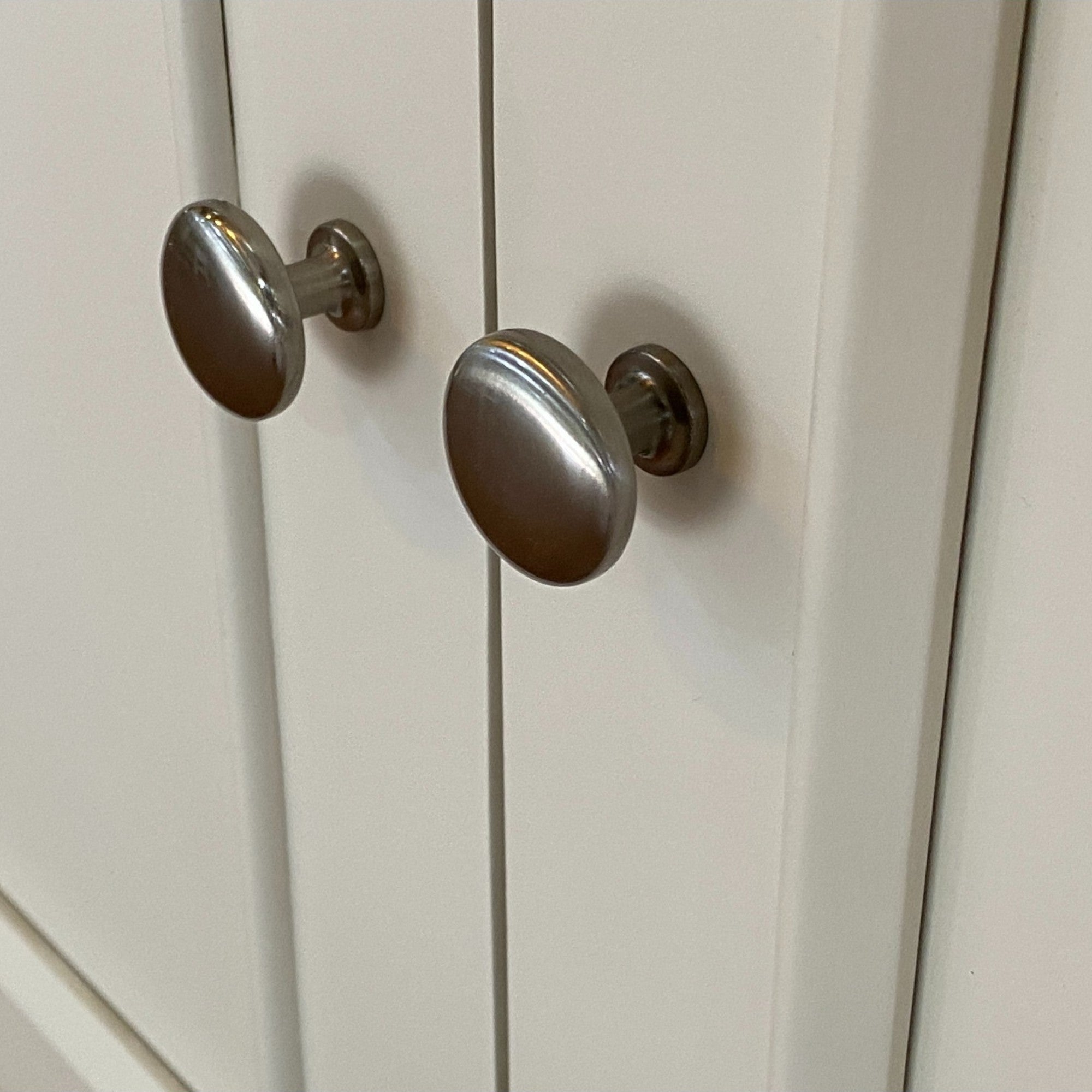 Close-up of silver cabinet knobs on a white wooden door
