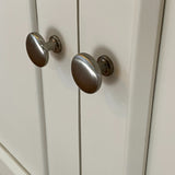 Close-up of silver cabinet knobs on a white wooden door