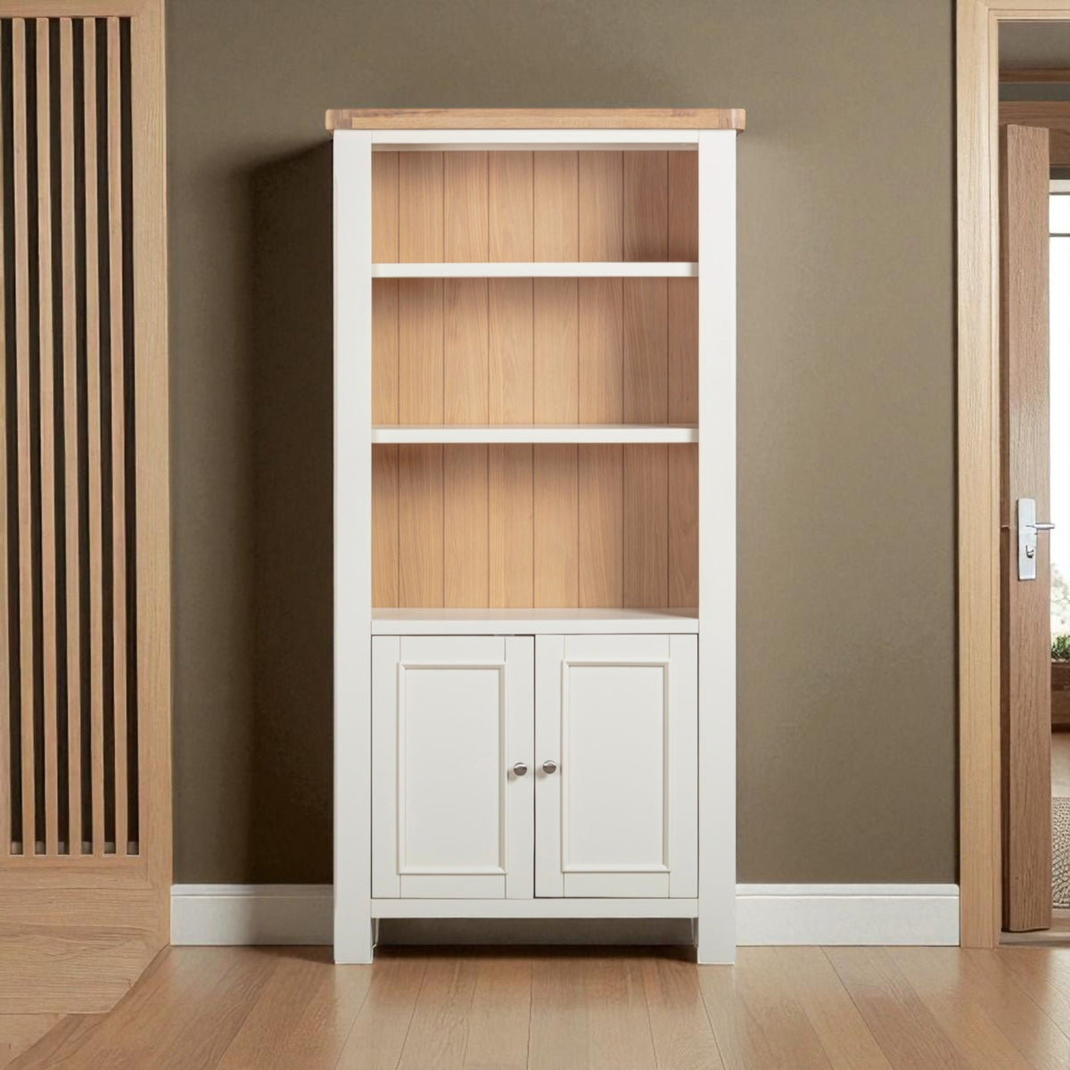 Tall bookshelf with wooden shelves and white base cabinet against a brown wall.