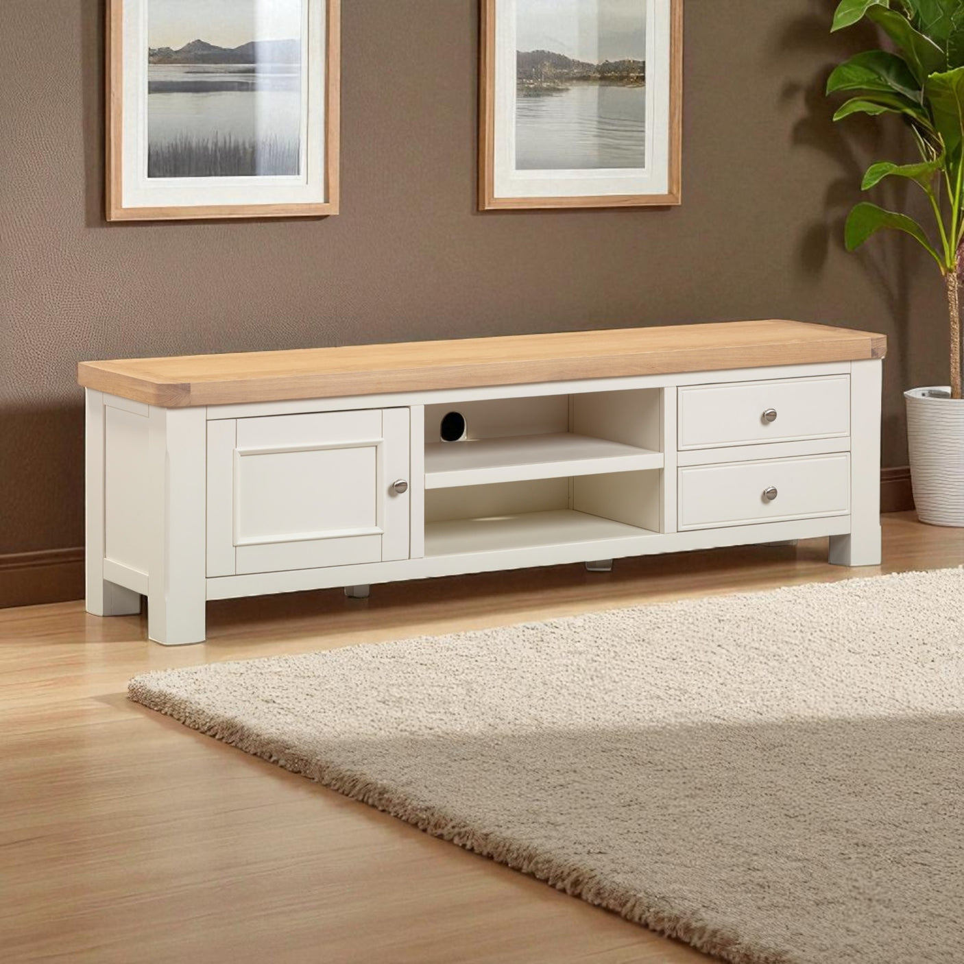 White TV stand with wooden top in a room with framed pictures and a plant.