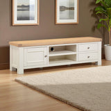 White TV stand with wooden top in a room with framed pictures and a plant.
