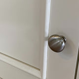 Metallic cabinet knob on a white cabinet door